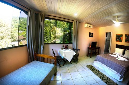 a room with two beds and a table and a window at Ponta Da Barca in Praia Vermelha