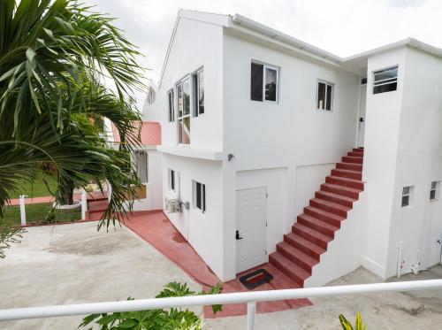 a white house with stairs and palm trees at Charming Valley View Studio in Saint Johnʼs