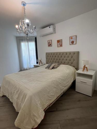 a bedroom with a large bed and a chandelier at Premium tower apart Parking gratis in Cordoba