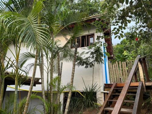 una pequeña casa con una valla y algunas palmeras en Pousada Peninsula de Buzios, en Búzios