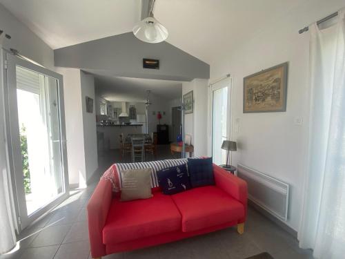 - un canapé rouge dans le salon doté de fenêtres dans l'établissement Maison raffinée au cœur de La Tranche, proche plage, parking et terrasse - FR-1-22-188, à La Tranche-sur-Mer