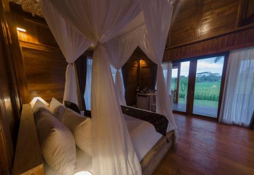 a bedroom with a canopy bed with white pillows at Mathura Ubud in Ubud