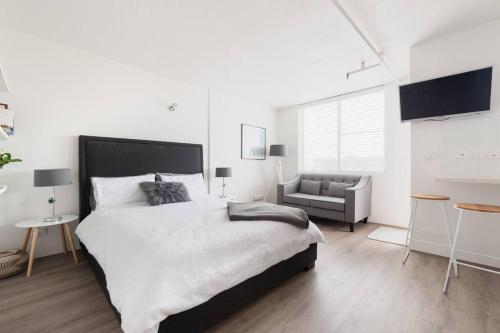 a white bedroom with a large bed and a couch at Bondi Beach Studio City Views and Balcony in Sydney