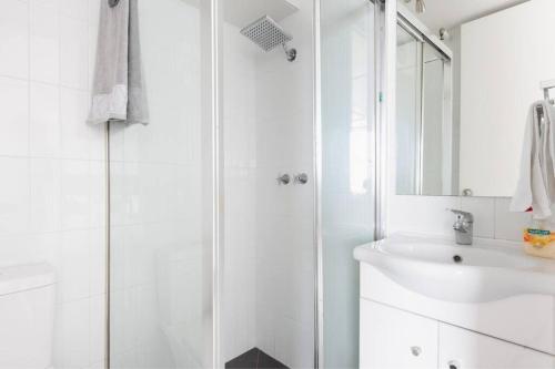 a white bathroom with a shower and a sink at Bondi Beach Studio City Views and Balcony in Sydney