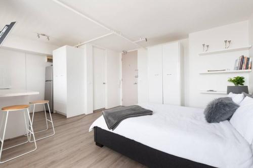a white bedroom with a large bed and white cabinets at Bondi Beach Studio City Views and Balcony in Sydney