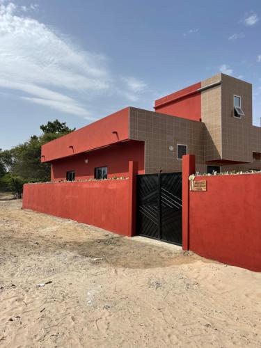 a building with a red fence in front of it at Auberge Andel Diabou SARR in Palmarin
