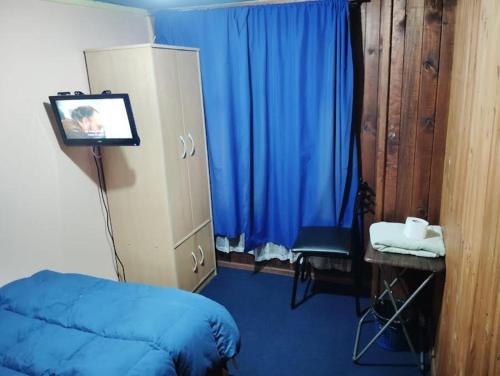 ein Schlafzimmer mit einem blauen Bett und einem TV. in der Unterkunft Pensión San Andrés in Concepción