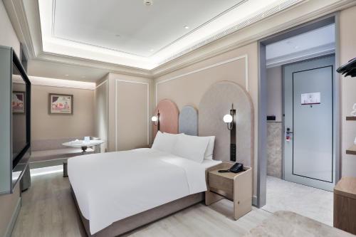 a bedroom with a large white bed and a tv at Mercure Hangzhou Xixi Zijingang in Hangzhou
