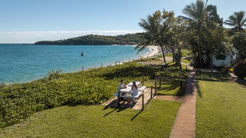 a woman sitting on a bench next to the ocean at Great Keppel Island Hideaway in Great Keppel