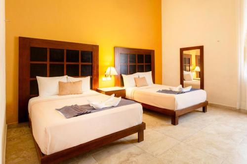 a hotel room with two beds and a mirror at Tecnohotel Casa Villamar in Progreso