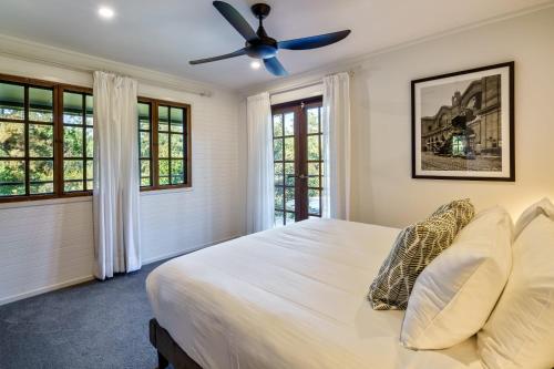 a bedroom with a white bed with a ceiling fan at Grove Hinterland Retreat - 15 mins to beach in Kiels Mountain