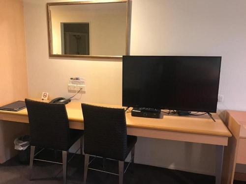 escritorio con monitor de ordenador y 2 sillas en Harbour City Motor Inn & Conference en Tauranga