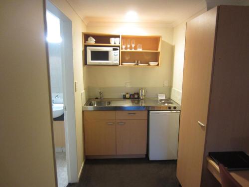 una pequeña cocina con fregadero y microondas en Harbour City Motor Inn & Conference, en Tauranga