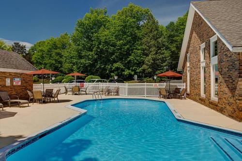 a swimming pool with tables and chairs next to a building at Residence Inn Hartford Windsor in Windsor