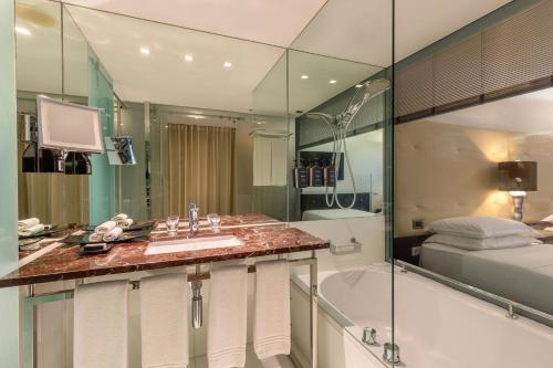a bathroom with a sink and a tub and a bed at Sheraton Lisboa Hotel & Spa in Lisbon