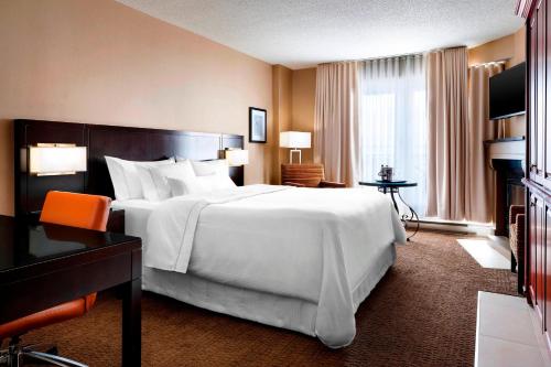 モントランブランにあるLe Westin Tremblantの白い大型ベッド1台と窓が備わるホテルルームです。
