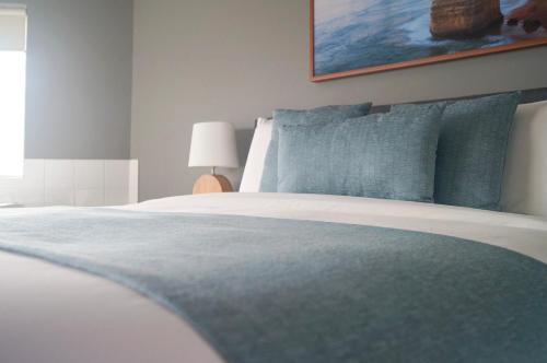 a bedroom with a large bed with blue pillows at Waves Luxury Suites in Port Campbell