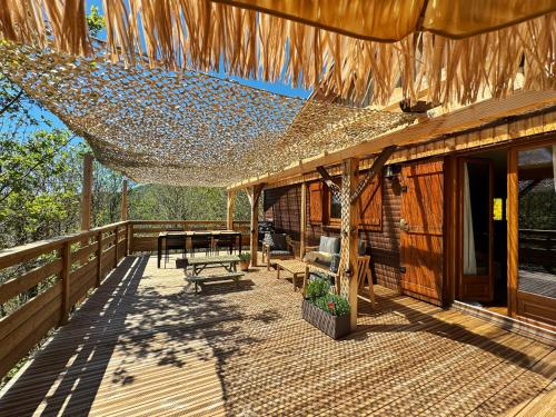 a wooden deck with a hammock and a house at Chalet de Dourbies in Dourbies