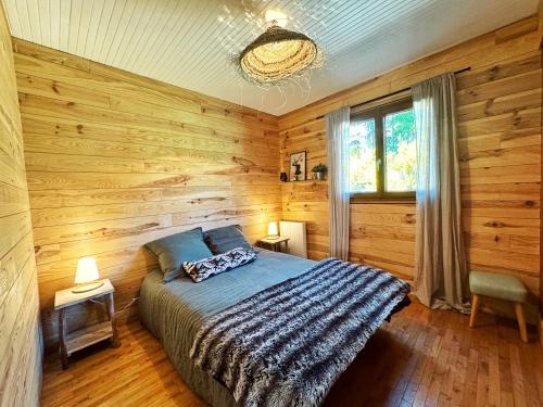 a bedroom with wooden walls and a bed and a window at Chalet de Dourbies in Dourbies
