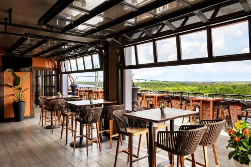 a restaurant with tables and chairs and large windows at The Bohemian Hotel Savannah Riverfront, Autograph Collection in Savannah