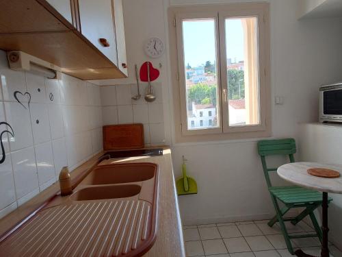 une cuisine avec un évier, une table et une fenêtre dans l'établissement Port-Vendres T2 charmant proche port et commerces, 4 pers., confort assuré - FR-1-309-460, à Port-Vendres