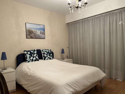 - une chambre avec un grand lit blanc et un lustre dans l'établissement Appartement 2P avec terrasses, parking privé, à 100m des plages - Juan-les-Pins - FR-1-252-196, à Antibes
