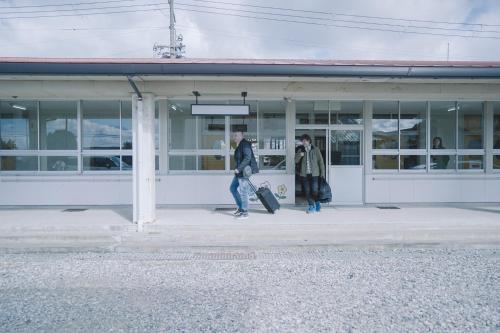 two people walking in front of a building with luggage at TADONO the bedroom in Kanaya