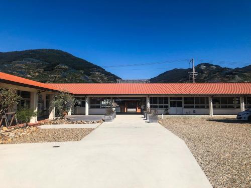 a building with a red roof with mountains in the background at TADONO the bedroom in Kanaya
