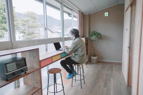 a man sitting at a desk with a laptop at TADONO the bedroom in Kanaya