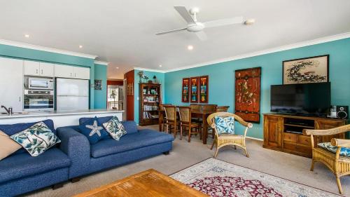 a living room with a blue couch and a kitchen at Sunrise Cove Holiday Apartments by Kingscliff Accommodation in Kingscliff