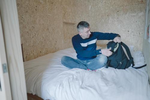 a man sitting on a bed with a backpack at TADONO the bedroom in Kanaya
