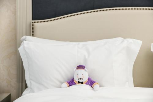 a stuffed teddy bear sitting on a bed at Hotel Bristol, A Luxury Collection Hotel, Warsaw in Warsaw
