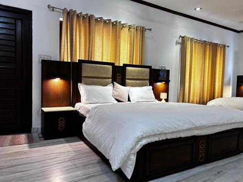 デヘラードゥーンにあるKings Villa 77 Home Stay Dehradunのベッドルーム1室(白いシーツと黄色のカーテンが備わるベッド2台付)