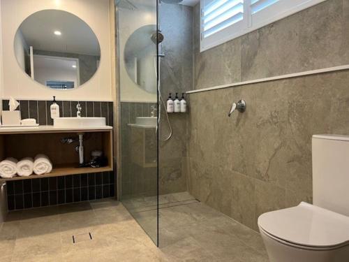 a bathroom with a shower and a toilet and a sink at Quality Hotel City Centre in Coffs Harbour