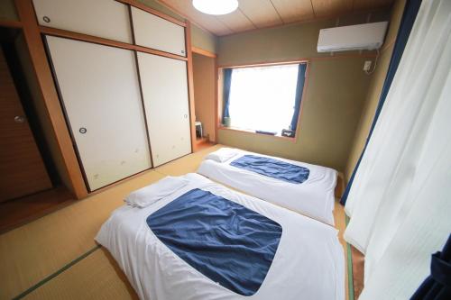 dwa łóżka w pokoju z oknem w obiekcie ulala hometown - Vacation STAY 09297v w mieście Kagoshima