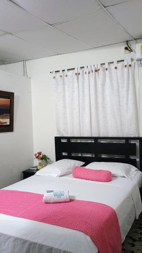 ChigorodóにあるHotel Acuariosのベッドルーム1室(ピンクと白のシーツが備わるベッド2台付)