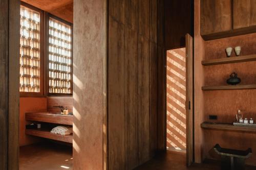 a bathroom with wooden walls and a sink and window at Further Hotel in Canggu