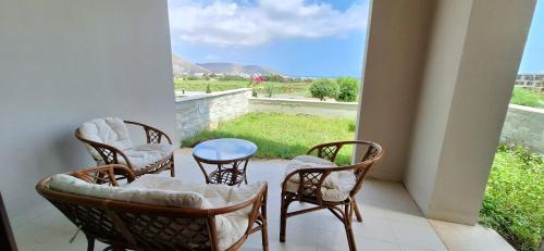 a porch with chairs and a table and a window at Wateera Jebel Sifah in As Sīfah