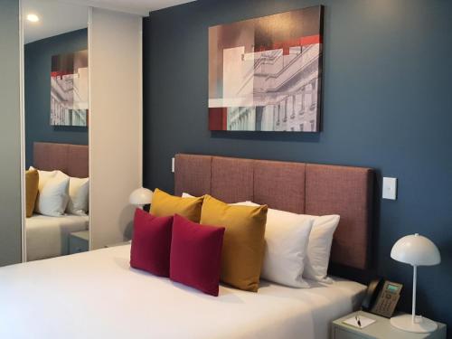 a bedroom with a bed with yellow and red pillows at La Quinta by Wyndham Parnell Auckland in Auckland