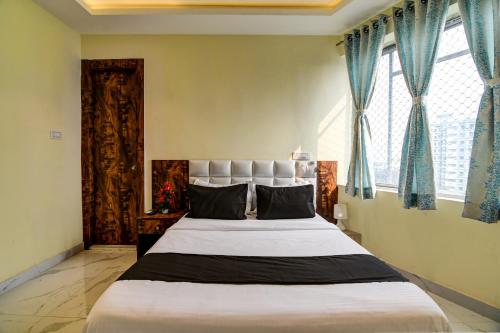 a bedroom with a large bed with blue curtains at Collection O The Hastings Club in Kolkata