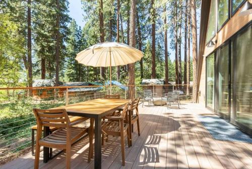 a wooden table with chairs and an umbrella on a deck at Brand New Modern A-Frame In Kings Beach Two Blocks From The Beach in Kings Beach