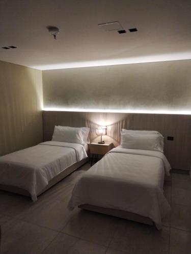 two beds in a hotel room with a light at Sonata 44 Hotel Laureles in Medellín