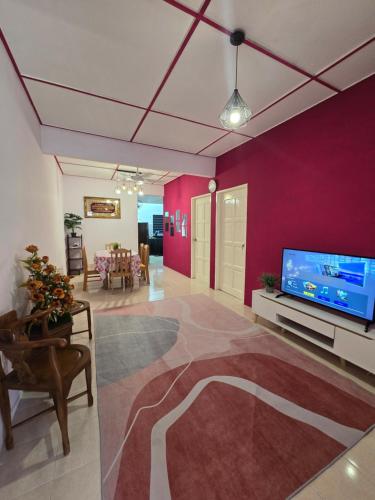a living room with a red wall and a flat screen tv at Al Mughni Homestay Temerloh with Private Pool in Temerloh