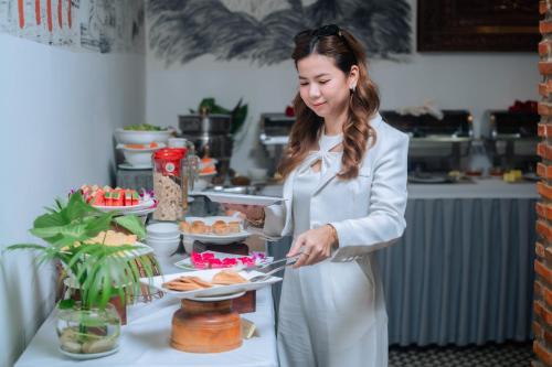 a woman in a kitchen holding a plate of food at Home Chic Hotel in Phnom Penh
