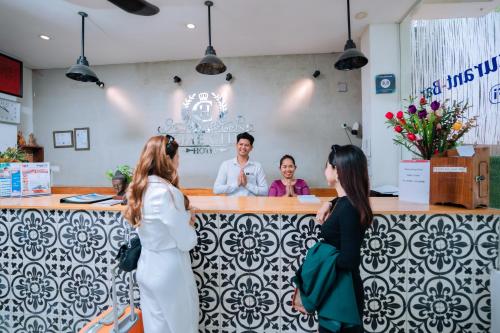 a group of people standing around a bar with a man at Home Chic Hotel in Phnom Penh