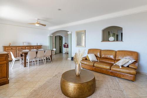 un salon avec un canapé en cuir marron et une table dans l'établissement Le Manon, vue imprenable sur la baie du Lavandou, au Lavandou