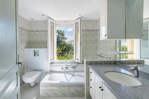 une salle de bain avec une baignoire, un lavabo et des toilettes dans l'établissement Le Manon, vue imprenable sur la baie du Lavandou, au Lavandou