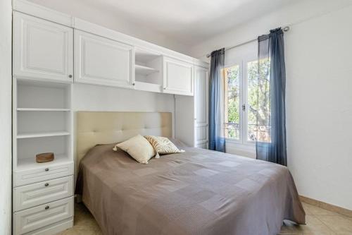 - une chambre avec un lit avec des placards blancs et une fenêtre dans l'établissement Le Manon, vue imprenable sur la baie du Lavandou, au Lavandou