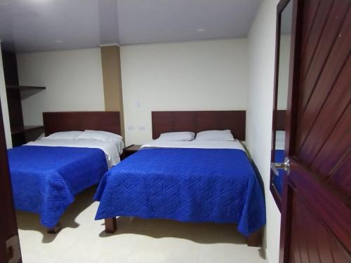 two beds in a room with blue sheets at Hotel Rialto Suite in Pasto