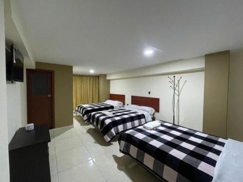 a room with three beds with black and white sheets at Hotel Rialto Suite in Pasto